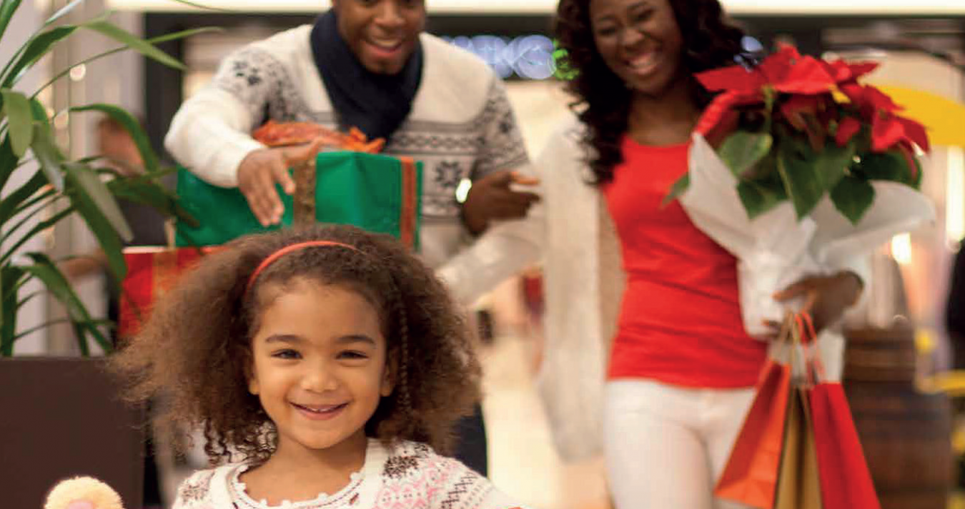 Família no shopping com presentes nas mãos.